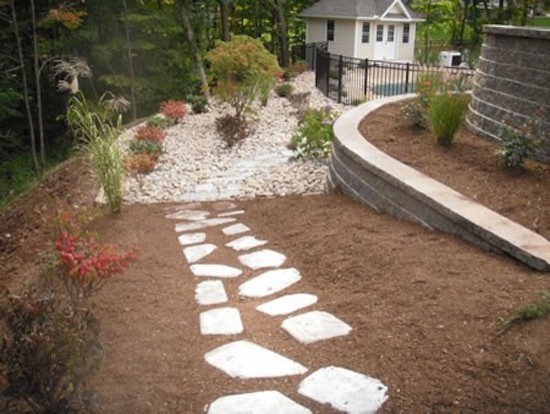 Photo of a mid-sized traditional side yard full sun xeriscape for summer in Bridgeport with a garden path and natural stone pavers.