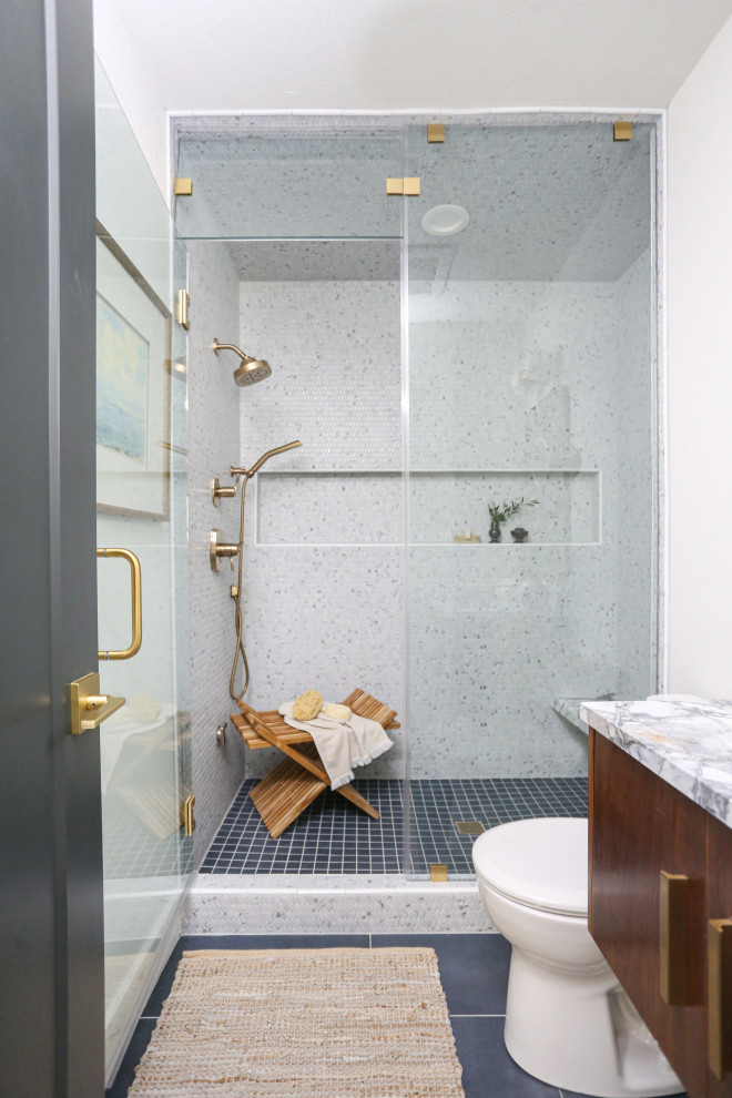 Exempel på ett mellanstort 60 tals vit vitt bastu, med släta luckor, skåp i mörkt trä, en dusch i en alkov, en toalettstol med hel cisternkåpa, vit kakel, vita väggar, klinkergolv i porslin, ett undermonterad handfat, marmorbänkskiva, blått golv och dusch med gångjärnsdörr