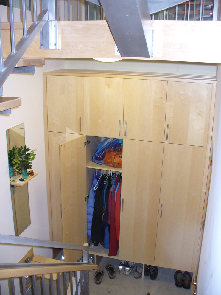 This is an example of a mid-sized contemporary gender-neutral built-in wardrobe in Burlington with flat-panel cabinets, light wood cabinets and porcelain floors.