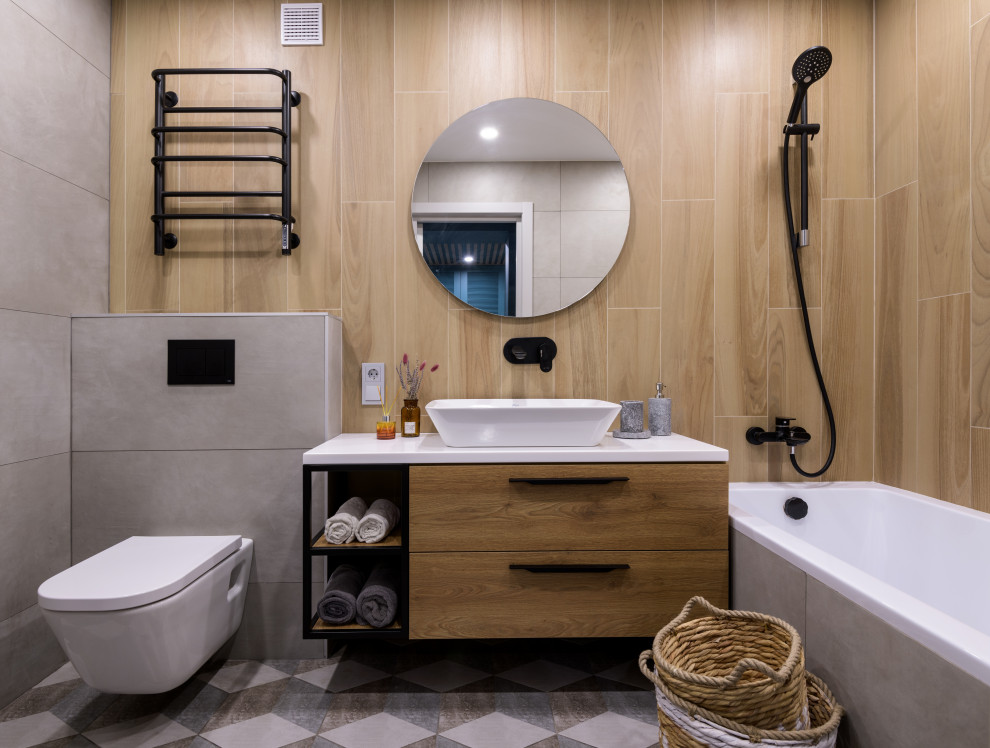 Exempel på ett mellanstort modernt vit vitt en-suite badrum, med släta luckor, skåp i mellenmörkt trä, ett undermonterat badkar, en vägghängd toalettstol, grå kakel, keramikplattor, beige väggar, klinkergolv i porslin, ett nedsänkt handfat, bänkskiva i akrylsten, flerfärgat golv och en dusch/badkar-kombination