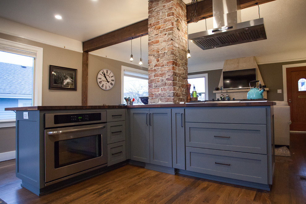 Small transitional l-shaped dark wood floor and brown floor open concept kitchen photo in Seattle with a farmhouse sink, shaker cabinets, gray cabinets, stainless steel appliances, an island, granite countertops, white backsplash, porcelain backsplash and beige countertops