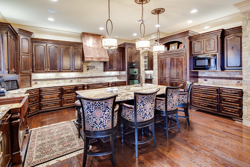 Inspiration for a large transitional u-shaped dark wood floor and brown floor enclosed kitchen remodel in Austin with a farmhouse sink, raised-panel cabinets, dark wood cabinets, granite countertops, beige backsplash, stone tile backsplash, paneled appliances, an island and beige countertops