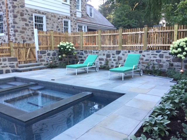 This is an example of a large traditional backyard rectangular lap pool in Philadelphia with a hot tub and concrete pavers.