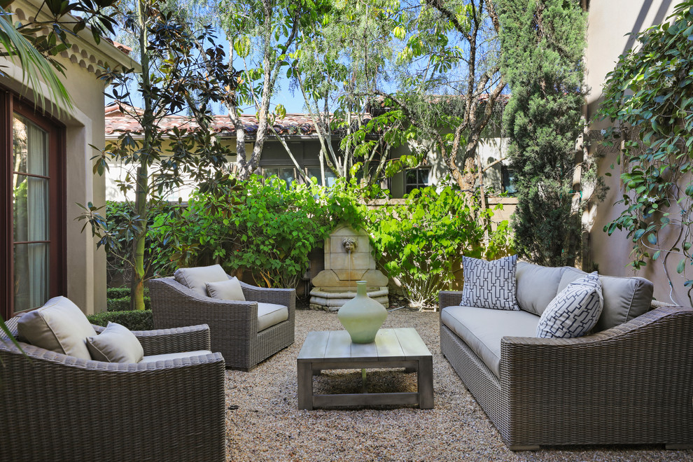 Mediterranean backyard patio in Orange County with a water feature, gravel and no cover.