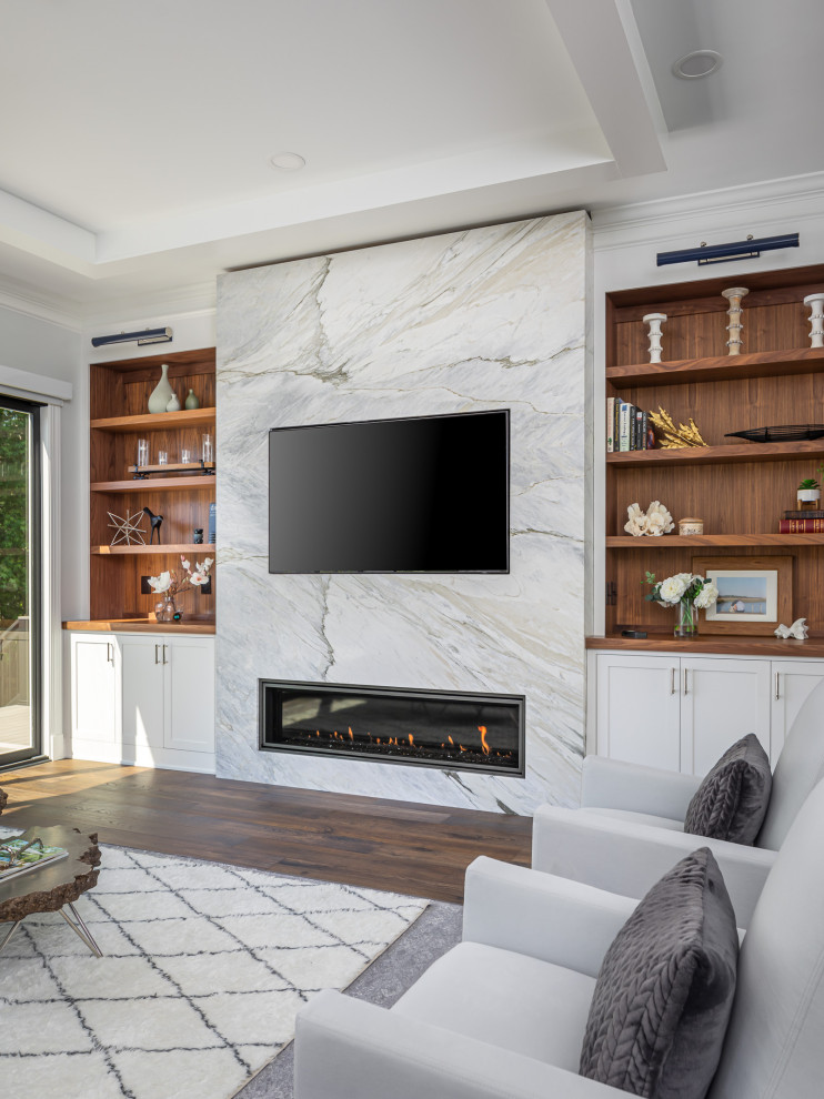 ローリーにある高級な中くらいなトランジショナルスタイルのおしゃれなLDK (白い壁、無垢フローリング、標準型暖炉、石材の暖炉まわり、埋込式メディアウォール、茶色い床、表し梁) の写真