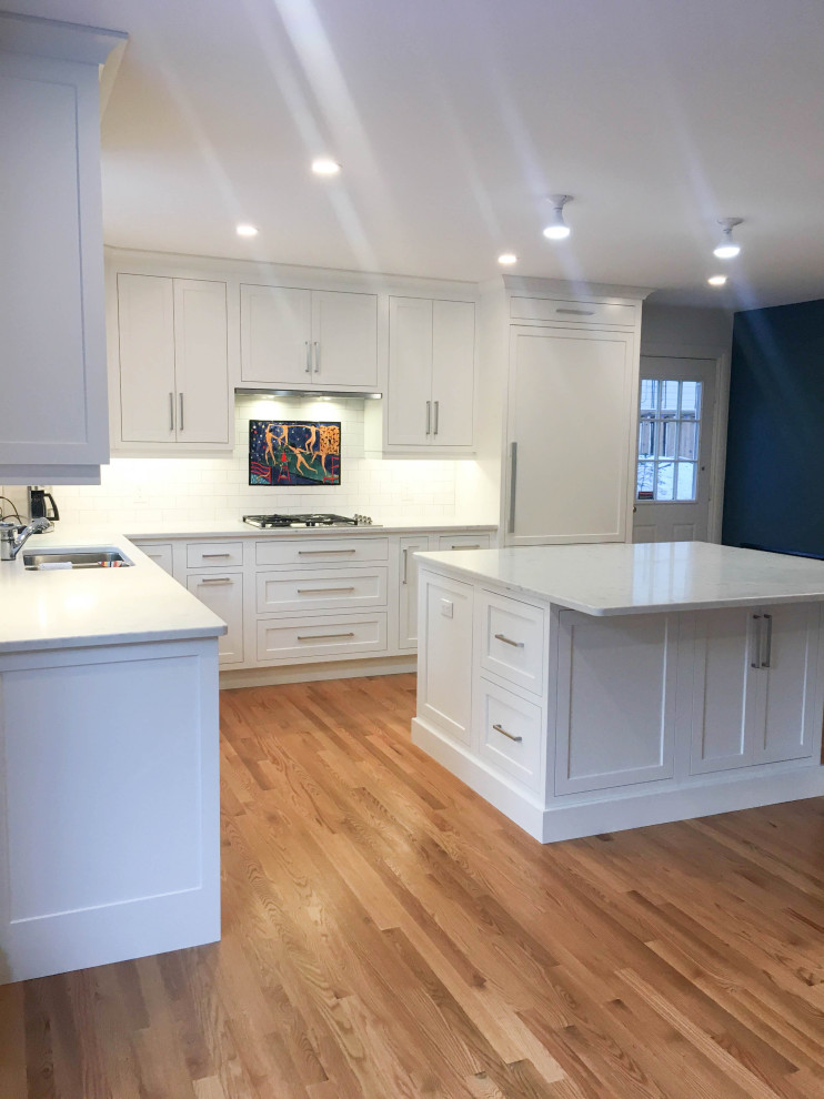 Inspiration for a large transitional u-shaped light wood floor and beige floor eat-in kitchen remodel with a double-bowl sink, shaker cabinets, white cabinets, quartzite countertops, white backsplash, subway tile backsplash, stainless steel appliances, an island and white countertops