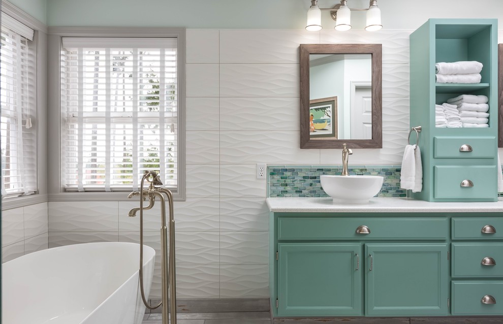 This is an example of a large transitional master bathroom in Seattle with recessed-panel cabinets, turquoise cabinets, a freestanding tub, a corner shower, white tile, glass tile, white walls, porcelain floors, a vessel sink, engineered quartz benchtops, grey floor and a hinged shower door.