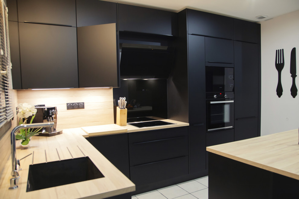 Photo of a mid-sized modern l-shaped open plan kitchen in Lyon with a single-bowl sink, beaded inset cabinets, black cabinets, solid surface benchtops, timber splashback, panelled appliances, ceramic floors, with island and beige floor.