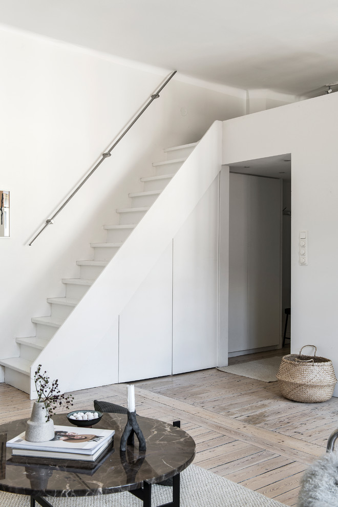 Design ideas for a small scandinavian painted wood straight staircase in Stockholm with painted wood risers and metal railing.