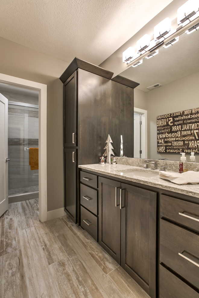 Inspiration for a transitional porcelain tile drop-in bathtub remodel in Omaha with shaker cabinets, dark wood cabinets, an undermount sink and quartzite countertops