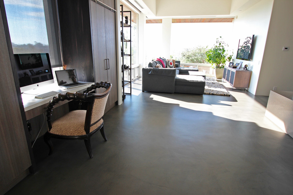Example of a large trendy built-in desk concrete floor and gray floor study room design in San Diego with white walls