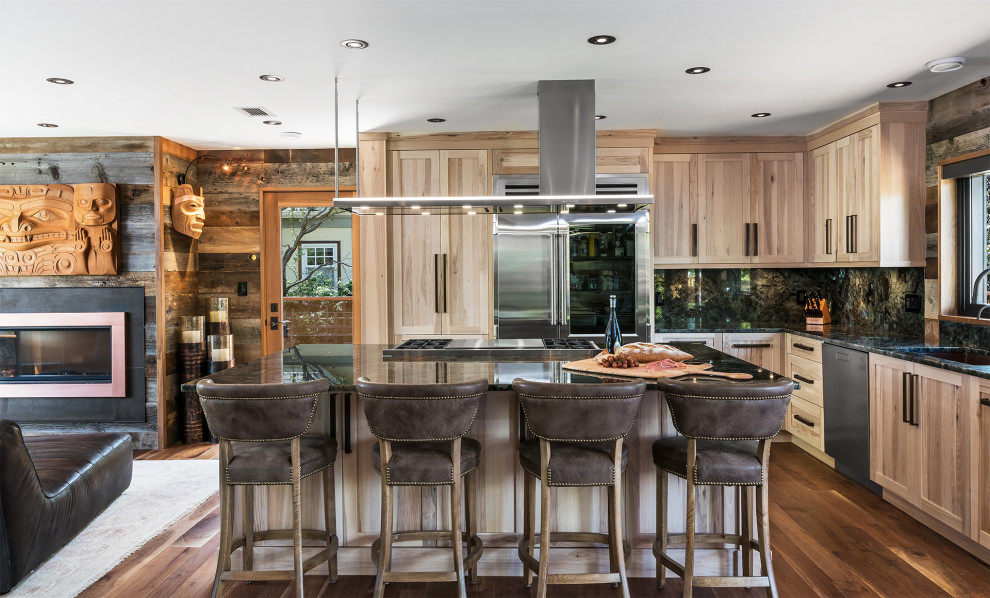 Example of a mid-sized mountain style l-shaped medium tone wood floor and brown floor open concept kitchen design with an undermount sink, shaker cabinets, light wood cabinets, granite countertops, granite backsplash, stainless steel appliances, an island, black backsplash and black countertops
