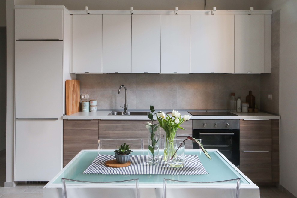 This is an example of a small scandinavian single-wall eat-in kitchen in Milan with an undermount sink, flat-panel cabinets, white cabinets, grey splashback, ceramic splashback, stainless steel appliances and no island.