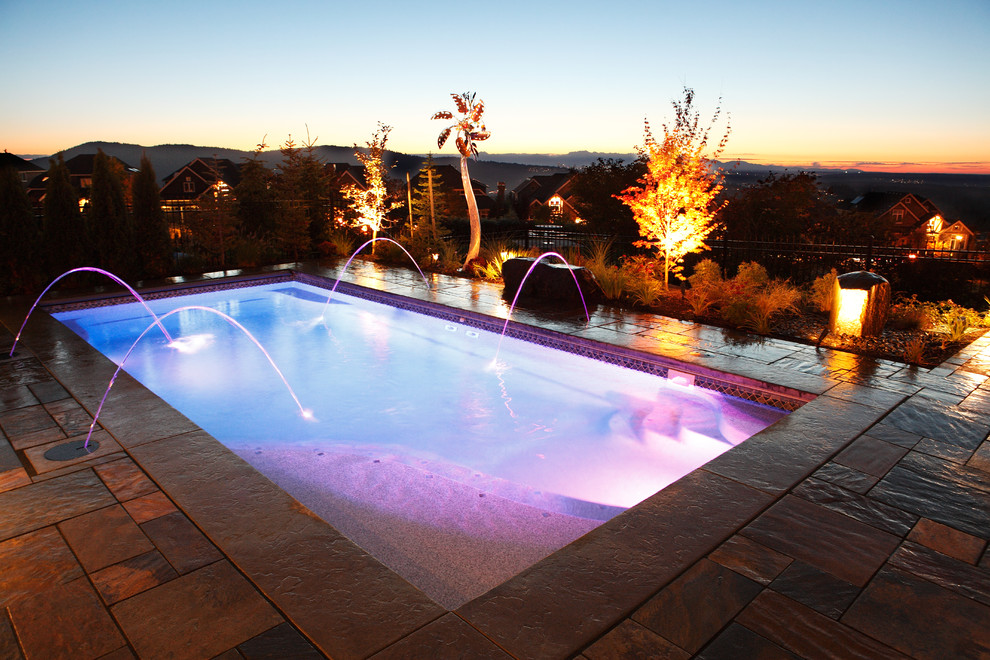 Mid-sized country backyard rectangular pool in Seattle with natural stone pavers.