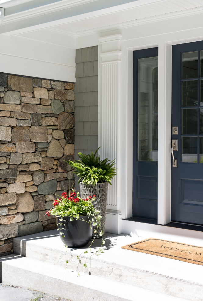 This is an example of a traditional two-storey grey house exterior in Boston with stone veneer and shingle siding.