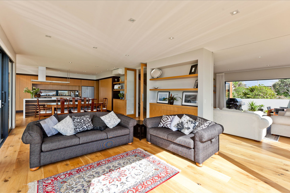 Large contemporary enclosed living room in Auckland with white walls and light hardwood floors.