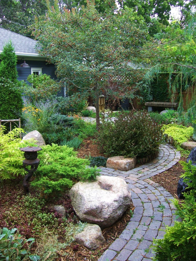 This is an example of an asian backyard formal garden in Minneapolis with a garden path and natural stone pavers.