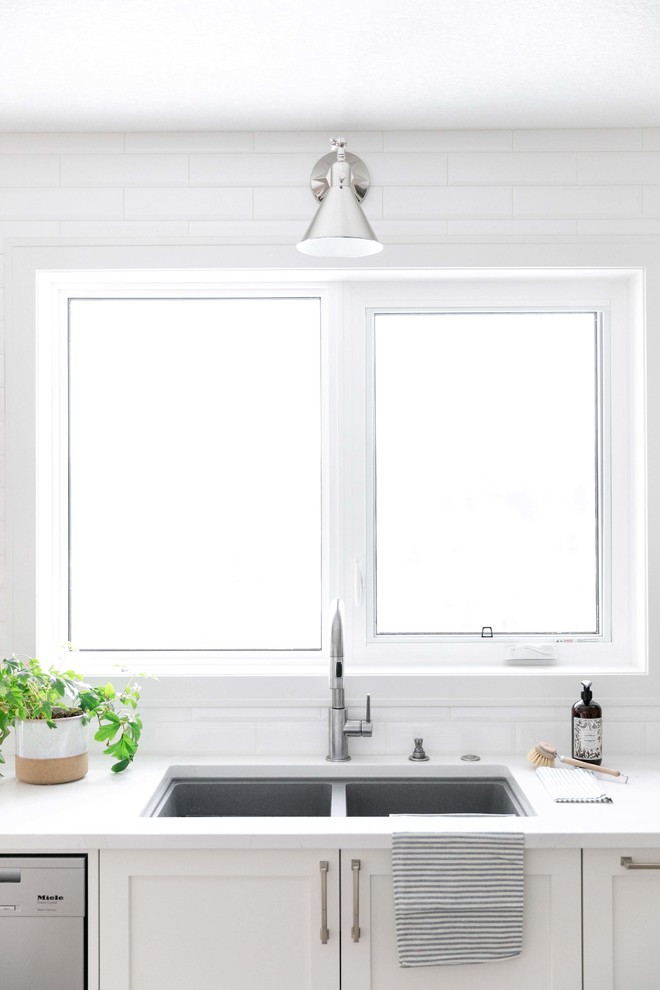 Large transitional u-shaped medium tone wood floor and brown floor eat-in kitchen photo in Calgary with an undermount sink, shaker cabinets, white cabinets, quartzite countertops, white backsplash, subway tile backsplash, stainless steel appliances, an island and white countertops