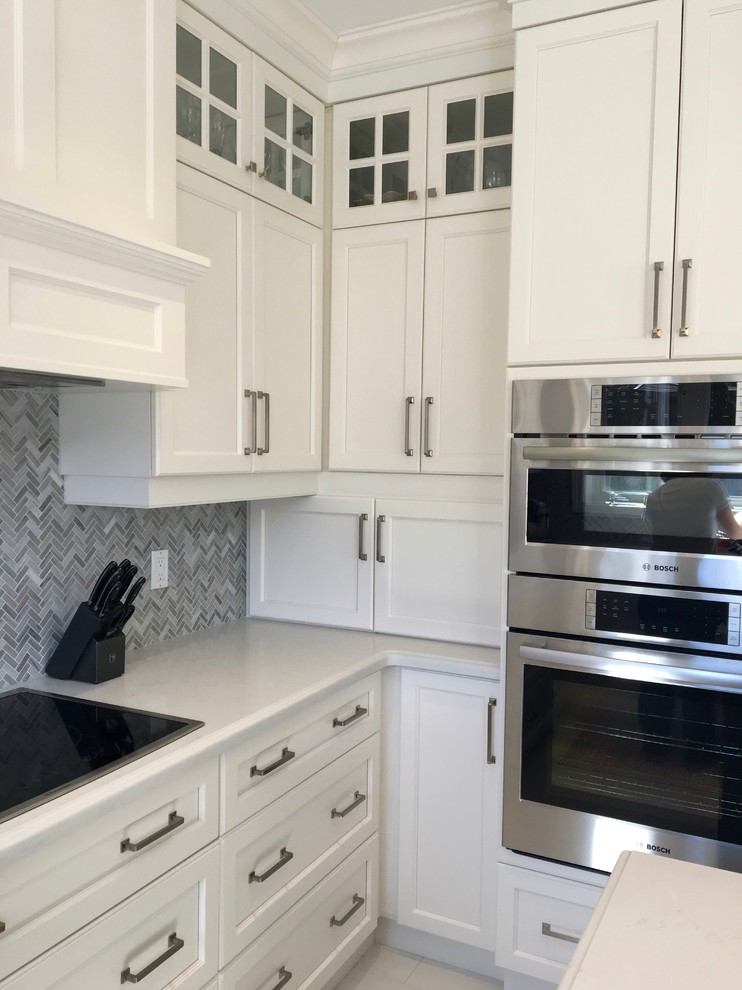 Enclosed kitchen - mid-sized transitional u-shaped porcelain tile enclosed kitchen idea in Toronto with a double-bowl sink, recessed-panel cabinets, white cabinets, quartz countertops, gray backsplash, mosaic tile backsplash, stainless steel appliances and an island