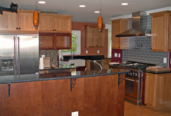 Eat-in kitchen - large transitional u-shaped medium tone wood floor eat-in kitchen idea in DC Metro with a farmhouse sink, shaker cabinets, medium tone wood cabinets, granite countertops, gray backsplash, subway tile backsplash, stainless steel appliances and a peninsula
