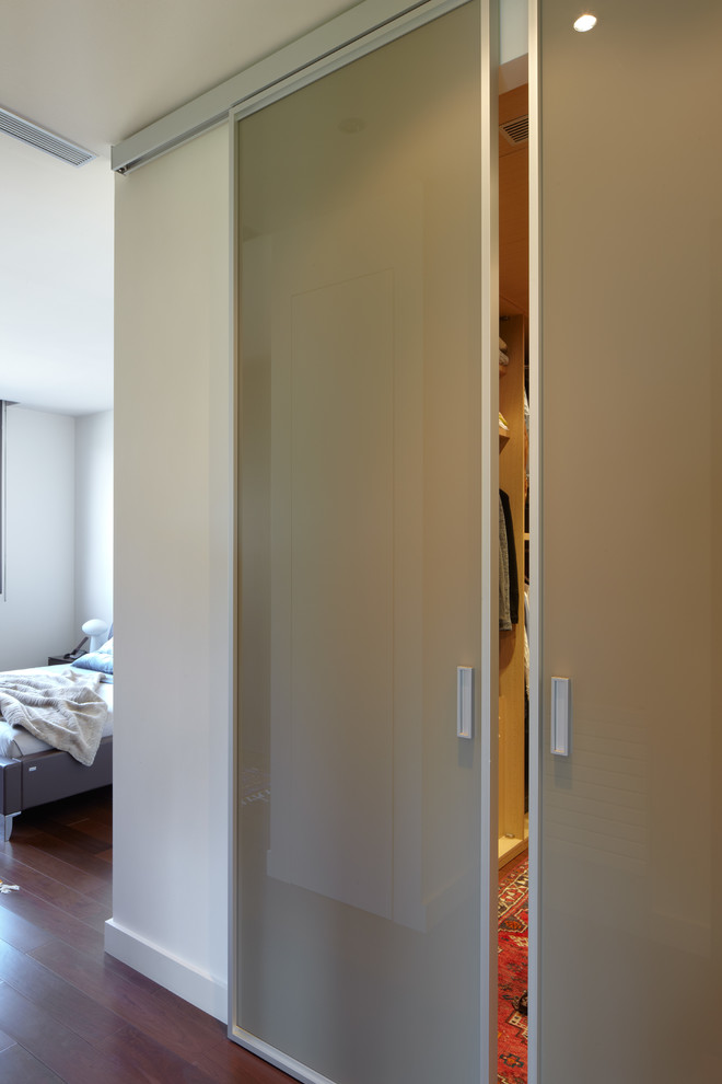 This is an example of a mid-sized transitional gender-neutral walk-in wardrobe in Barcelona with dark hardwood floors.