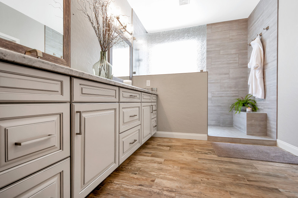 This is an example of a mid-sized transitional master bathroom in Phoenix with raised-panel cabinets, grey cabinets, an open shower, gray tile, porcelain tile, grey walls, porcelain floors, an undermount sink, granite benchtops, grey floor, an open shower, grey benchtops, a shower seat, a double vanity and a built-in vanity.