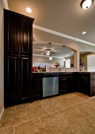 Eat-in kitchen - traditional galley ceramic tile eat-in kitchen idea in Other with a double-bowl sink, raised-panel cabinets, dark wood cabinets, granite countertops, beige backsplash, stone tile backsplash, stainless steel appliances and no island