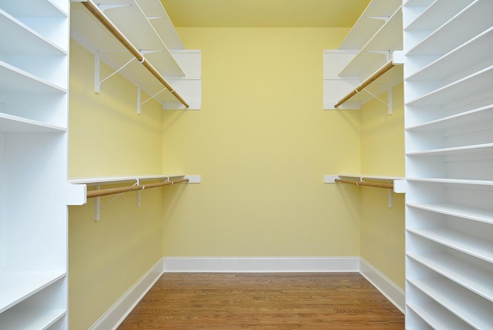 Design ideas for a large gender-neutral walk-in wardrobe in Raleigh with medium hardwood floors.