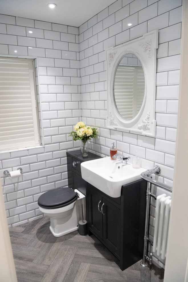 This is an example of a mid-sized traditional master bathroom in Hampshire with shaker cabinets, grey cabinets, an open shower, a one-piece toilet, white tile, ceramic tile, white walls, vinyl floors, a drop-in sink, wood benchtops, grey floor, an open shower and grey benchtops.