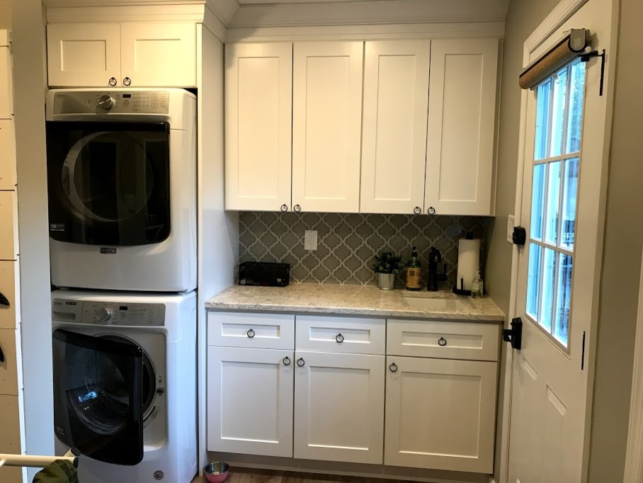 Inspiration for an arts and crafts galley laundry room in Philadelphia with an undermount sink, shaker cabinets, white cabinets, granite benchtops, vinyl floors and a stacked washer and dryer.