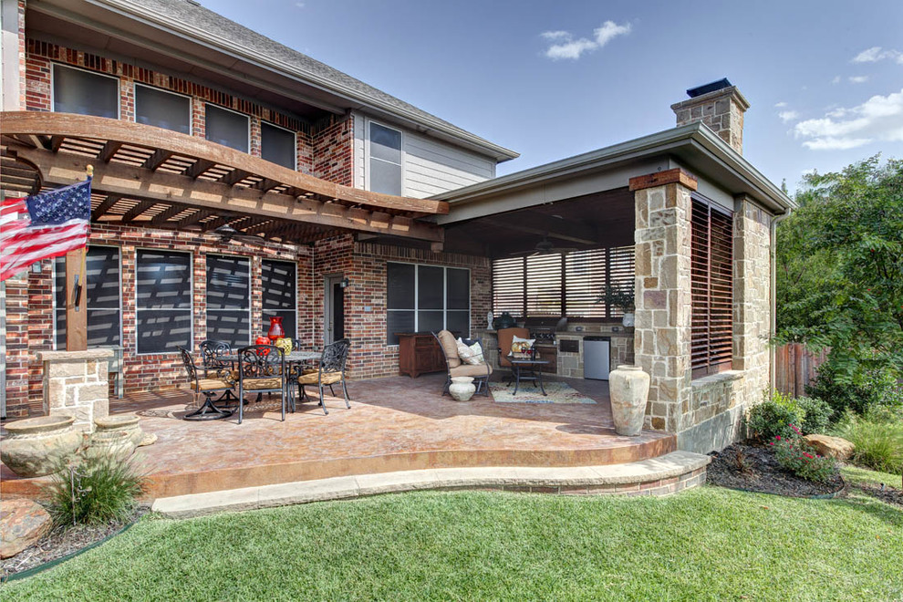 Mid-sized traditional backyard patio in Dallas with an outdoor kitchen, stamped concrete and a roof extension.