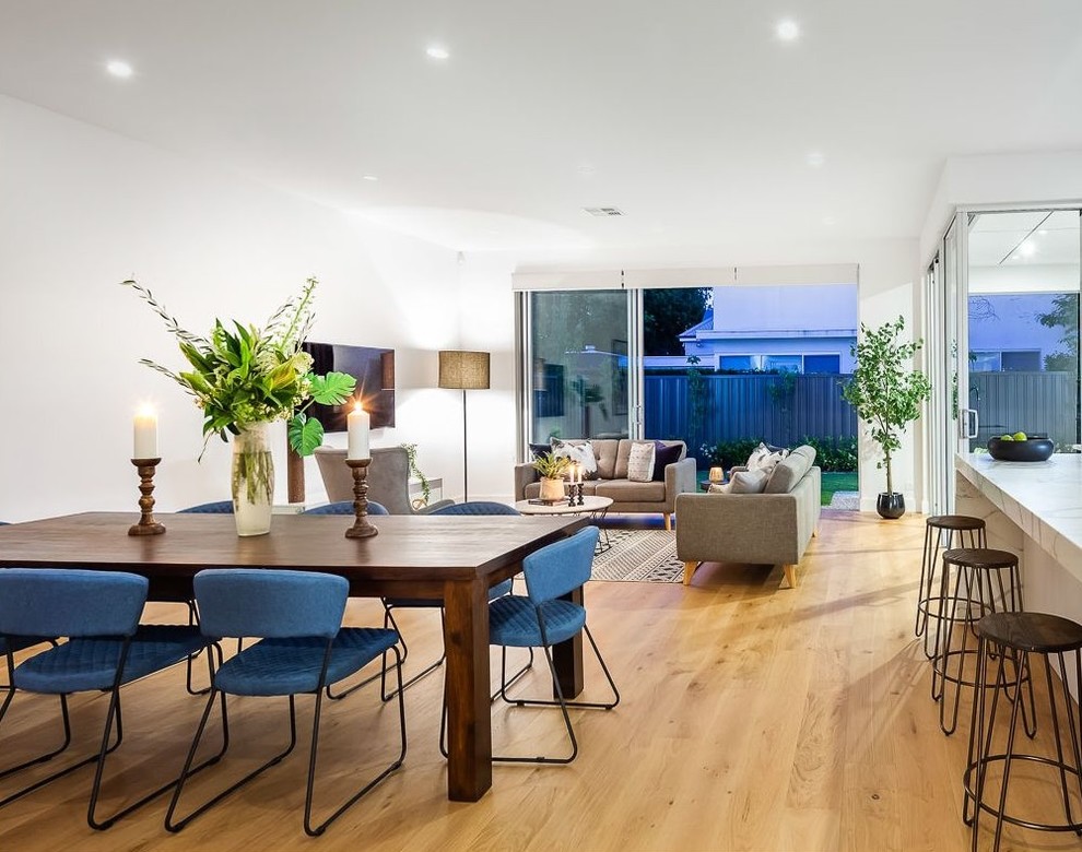 Contemporary open plan dining in Adelaide with white walls, medium hardwood floors, no fireplace and brown floor.
