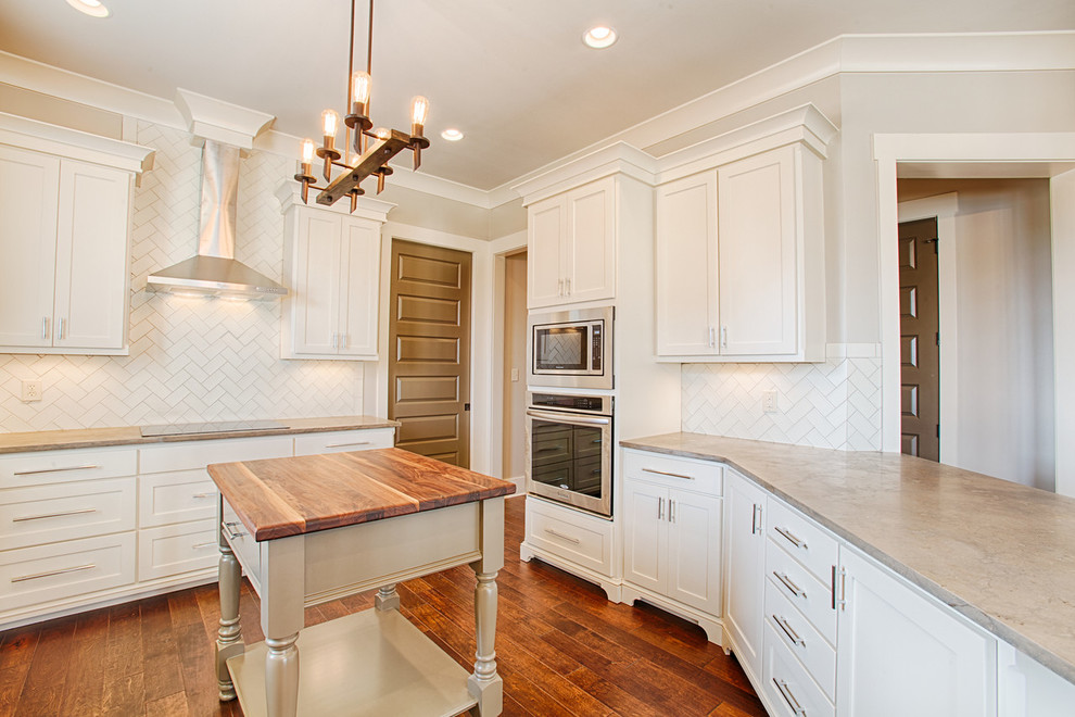 Mid-sized transitional kitchen photo with white cabinets, limestone countertops, white backsplash, ceramic backsplash, stainless steel appliances and an island