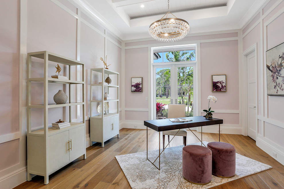 Inspiration for a transitional study room in Miami with pink walls, medium hardwood floors, no fireplace, a freestanding desk and brown floor.
