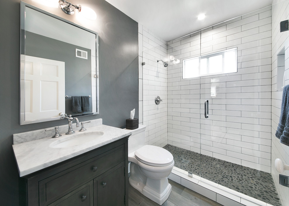 Inspiration for a transitional 3/4 bathroom in Los Angeles with recessed-panel cabinets, distressed cabinets, a double shower, a one-piece toilet, white tile, porcelain tile, grey walls, pebble tile floors, an undermount sink and marble benchtops.