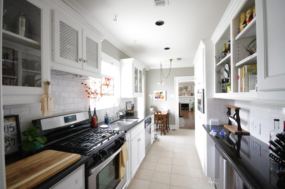 Mid-sized traditional galley eat-in kitchen in Houston with an undermount sink, glass-front cabinets, white cabinets, granite benchtops, white splashback, subway tile splashback, stainless steel appliances, porcelain floors and no island.