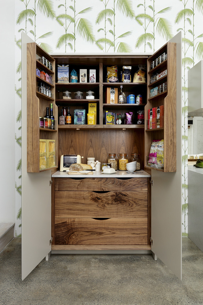 This is an example of a transitional kitchen pantry in London with dark wood cabinets and concrete floors.