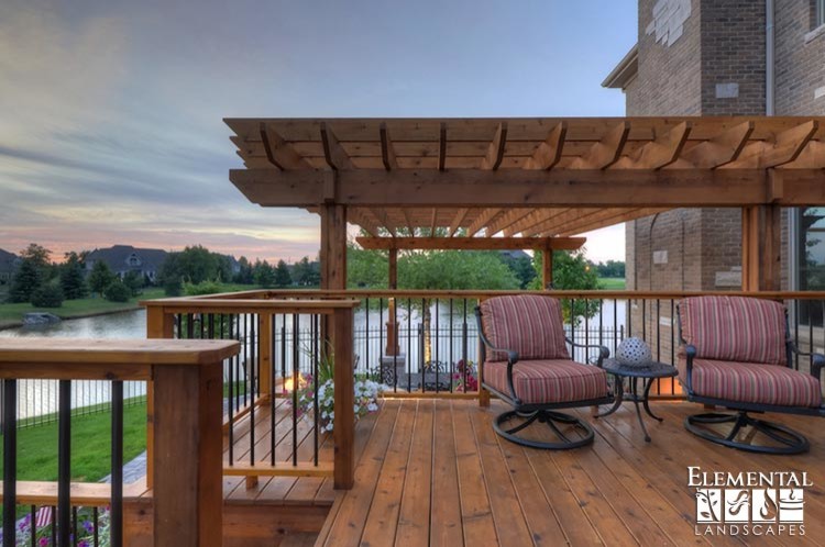 This is an example of a mid-sized country backyard deck in Chicago with an outdoor kitchen and a pergola.