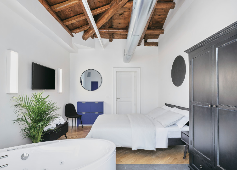 Foto di una camera da letto design con pareti bianche, pavimento in legno massello medio, pavimento marrone, travi a vista, soffitto a volta e soffitto in legno