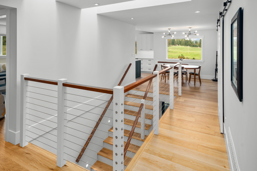 Inspiration for a country wood l-shaped staircase in Vancouver with cable railing and planked wall panelling.