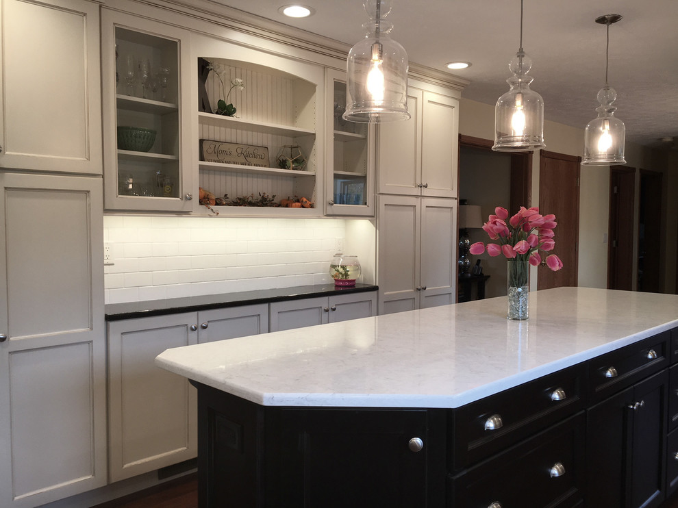 Inspiration for a large transitional medium tone wood floor and brown floor eat-in kitchen remodel with an undermount sink, flat-panel cabinets, white cabinets, granite countertops, white backsplash, porcelain backsplash, stainless steel appliances and an island