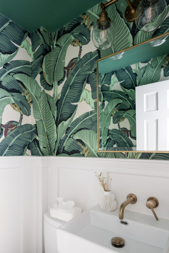 Imagen de aseo contemporáneo con sanitario de una pieza, paredes verdes, suelo con mosaicos de baldosas, lavabo suspendido y papel pintado