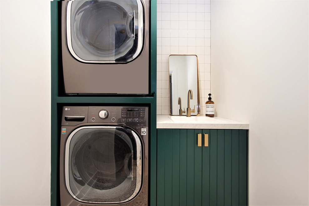 Small danish single-wall dedicated laundry room photo in Grand Rapids with green cabinets, quartzite countertops, white walls, a stacked washer/dryer, white countertops and a single-bowl sink