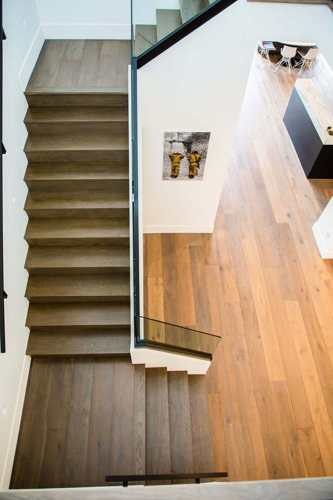 Photo of an expansive contemporary hallway in Los Angeles with white walls, medium hardwood floors and brown floor.