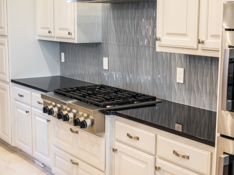 Inspiration for a large transitional u-shaped eat-in kitchen remodel with an undermount sink, raised-panel cabinets, white cabinets, granite countertops, gray backsplash, ceramic backsplash, stainless steel appliances and two islands