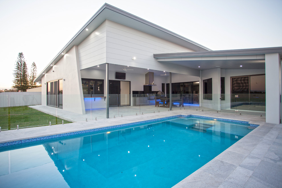 Mid-sized modern backyard rectangular pool in Other with tile.