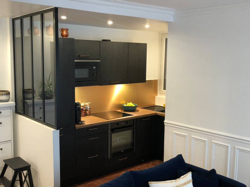 Photo of a mid-sized modern l-shaped open plan kitchen in Paris with an undermount sink, black cabinets, wood benchtops, yellow splashback, black appliances, terra-cotta floors, no island, brown floor and brown benchtop.
