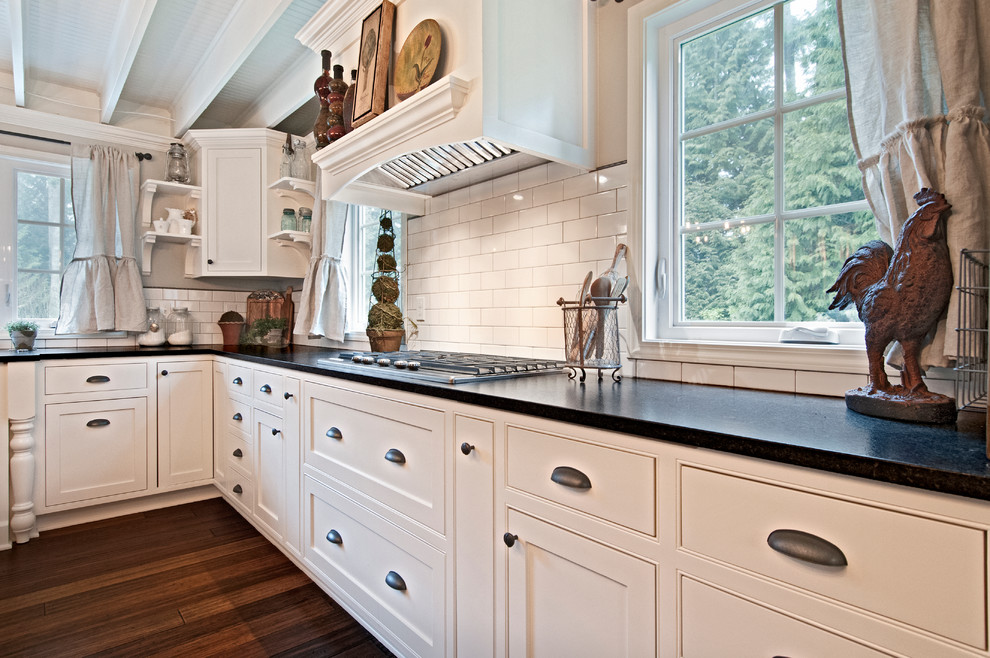 Inspiration for a country u-shaped eat-in kitchen in Seattle with a farmhouse sink, shaker cabinets, white cabinets, quartz benchtops, white splashback, subway tile splashback, stainless steel appliances, medium hardwood floors, with island and brown floor.