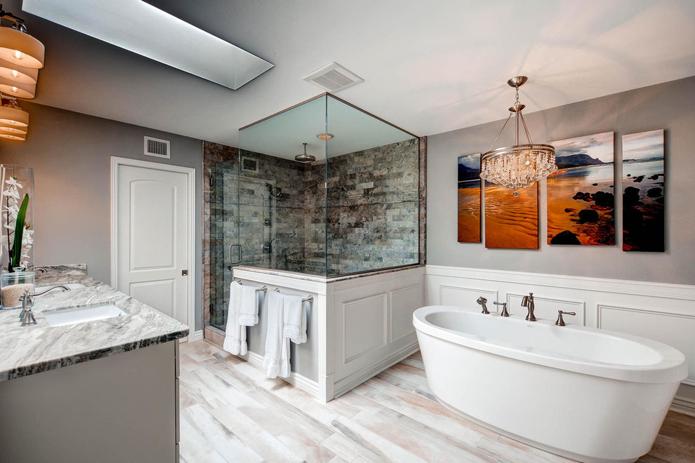 Example of a large transitional master gray tile and porcelain tile porcelain tile freestanding bathtub design in Phoenix with raised-panel cabinets, white cabinets, gray walls, an undermount sink and granite countertops