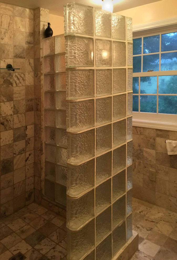 Modern inredning av ett litet badrum med dusch, med en dusch i en alkov, en toalettstol med separat cisternkåpa, travertinkakel, gula väggar, travertin golv, ett fristående handfat, bänkskiva i glas, med dusch som är öppen och beiget golv